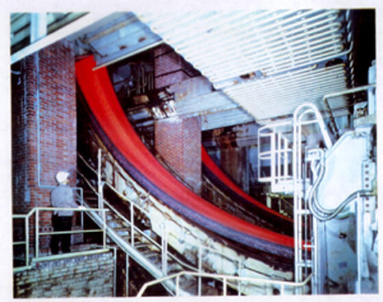 Red-hot strand curving through the spray chamber between support rolls